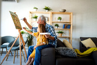Portrait of senior man, grandfather teaching children painting. Happy family time